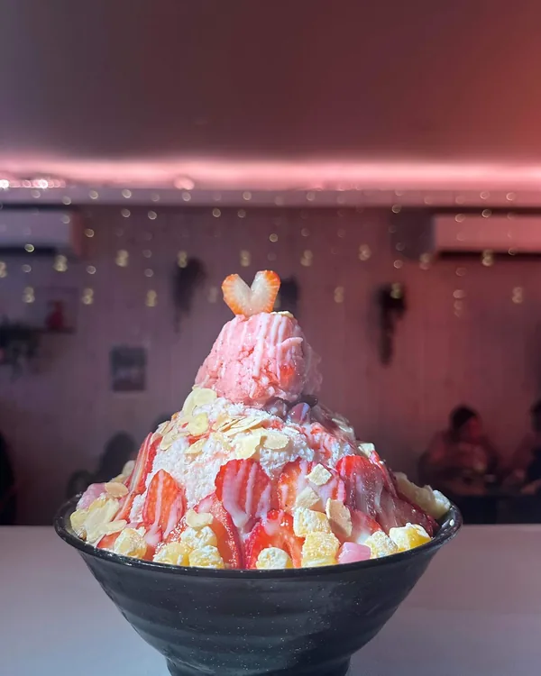 A strawberry bingsu with a little heart on top, under the pink lights along our ceiling
