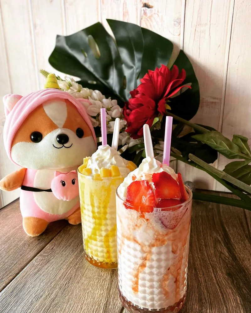 Two of our drinks on the table, one mango and one strawberry under cream, next to a little corgi toy